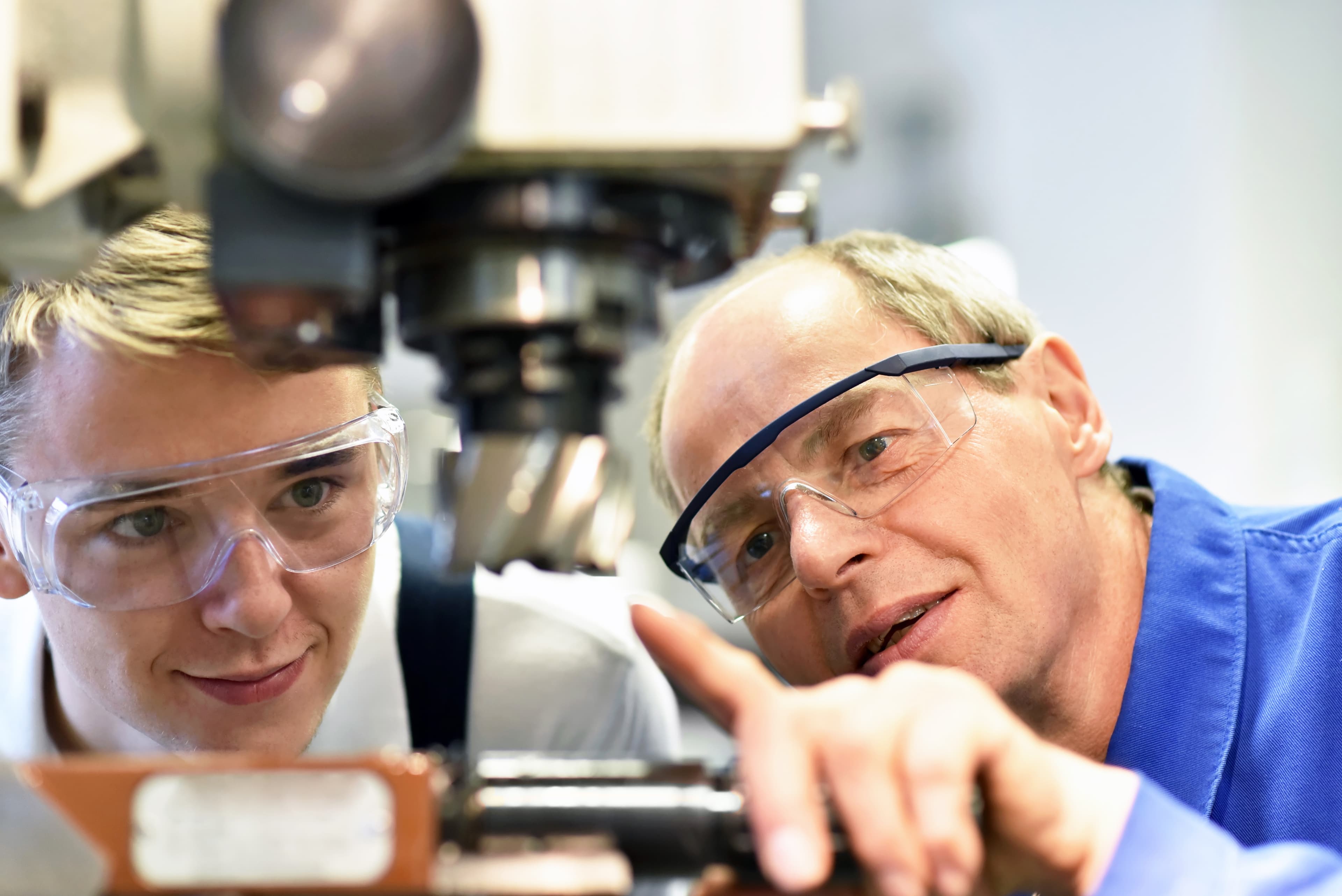 Berufsausbildung im Handwerk: Jugendlicher und Lehrer an einer CNC Maschine